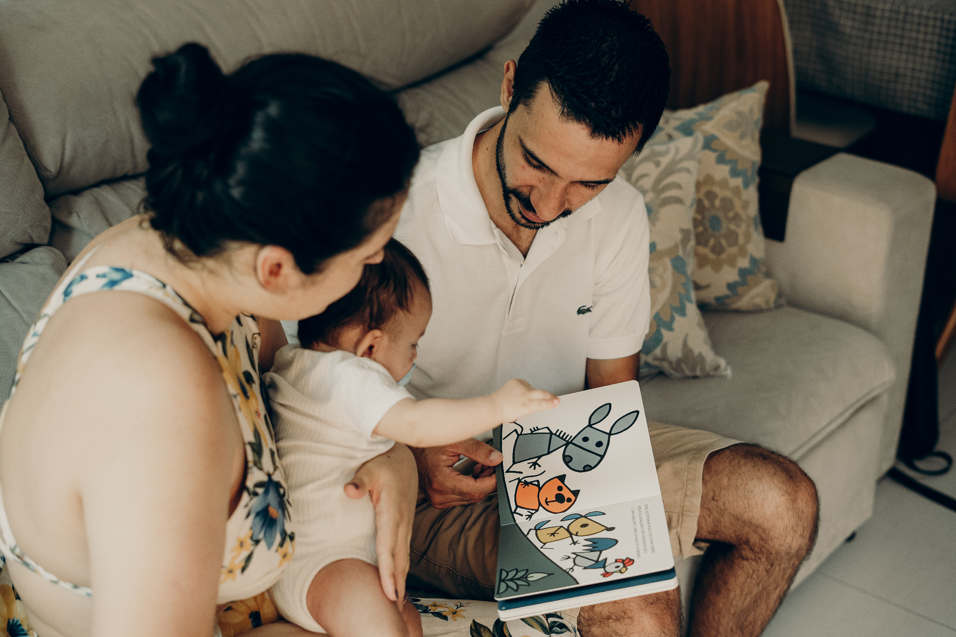 Casal lendo um livro com o bebê no colo — orientação parental